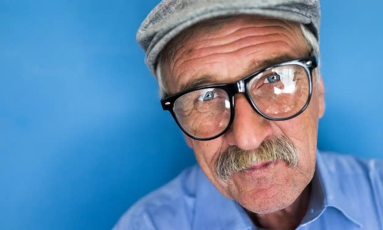 Un homme âgé de 70 ans avec un béret qui porte des lunettes de vue noires