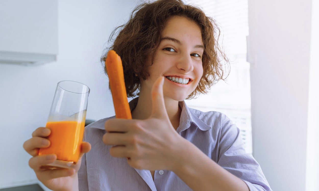 Jeune femme qui bois du jus de carottes