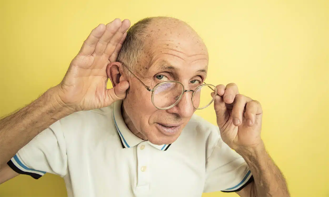 Une personne âgée qui fait le signe qu'il entend mal