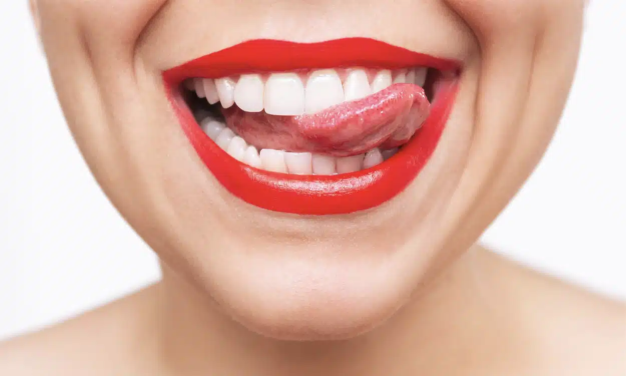 Gros plan sur le magnifique sourire d'une femme qui se passe la langue sur les dents